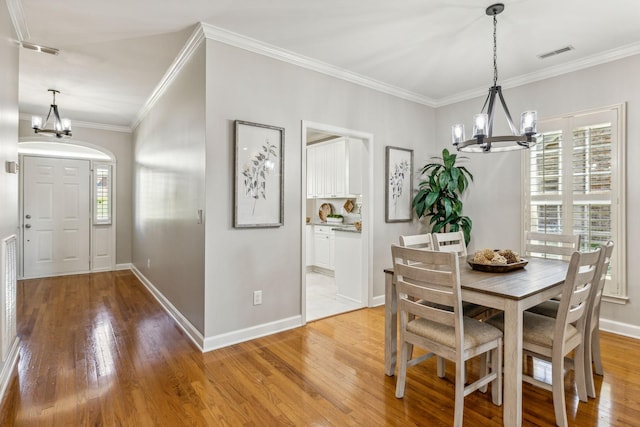 dining space featuring ornamental molding, a healthy amount of sunlight, a chandelier, and light hardwood / wood-style floors