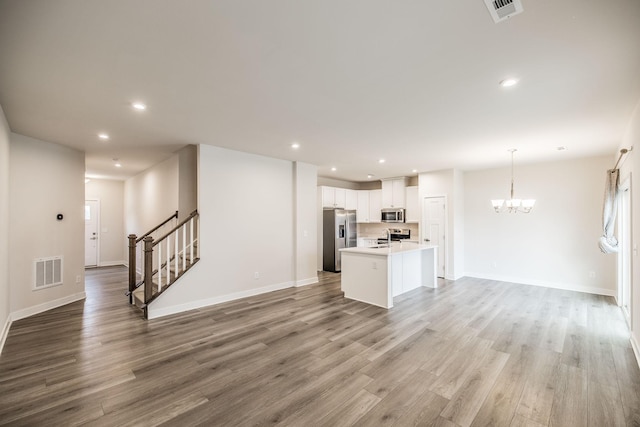 1335 Crescent Ridge Dr, Gallatin, TN 37066 - kitchen with a kitchen island with sink, white cabinetry, wood-type flooring, and appliances with stainless steel finishes