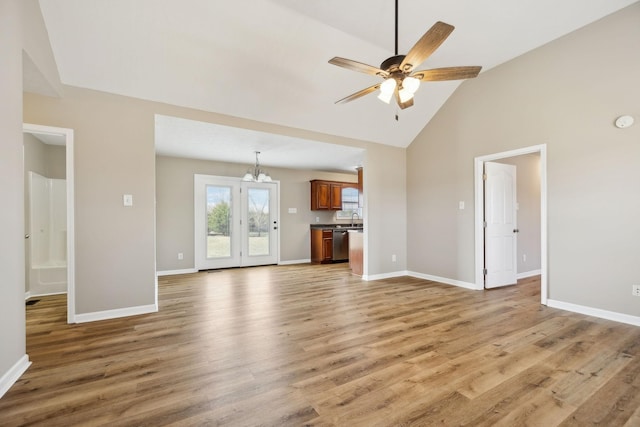 unfurnished living room with ceiling fan with notable chandelier, wood-type flooring, and high vaulted ceiling