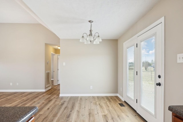 dining space with light hardwood / wood-style flooring, a chandelier, and vaulted ceiling