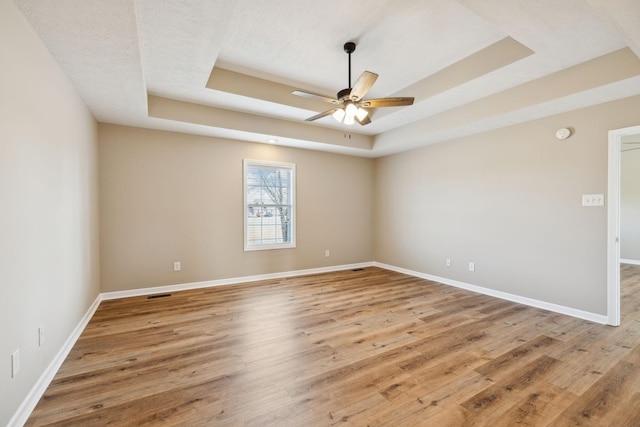 unfurnished room featuring hardwood / wood-style flooring, a raised ceiling, and ceiling fan