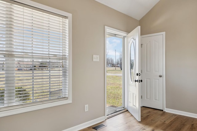 foyer entrance featuring vaulted ceiling, a healthy amount of sunlight, and light hardwood / wood-style flooring