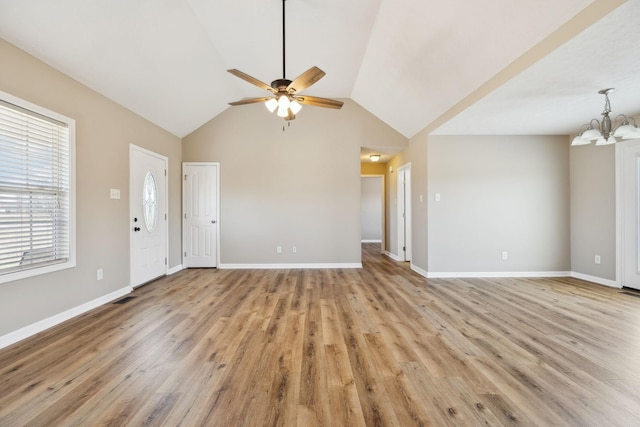 unfurnished living room featuring ceiling fan with notable chandelier, light hardwood / wood-style flooring, and vaulted ceiling