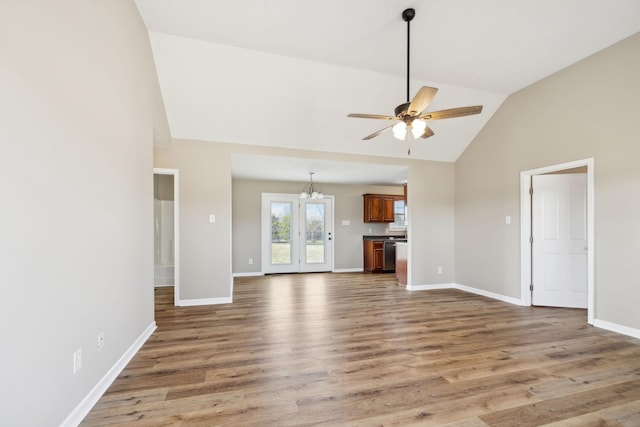 unfurnished living room featuring hardwood / wood-style flooring, ceiling fan with notable chandelier, and high vaulted ceiling