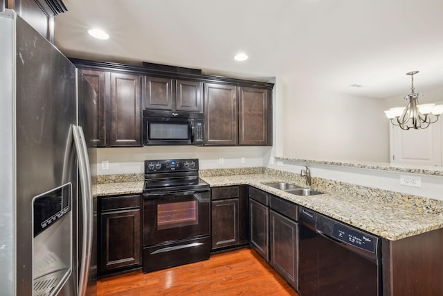 kitchen with hardwood / wood-style floors, pendant lighting, black appliances, sink, and kitchen peninsula