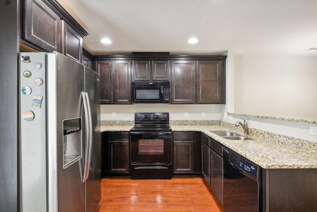 kitchen featuring sink, dark brown cabinetry, black appliances, light hardwood / wood-style floors, and light stone countertops