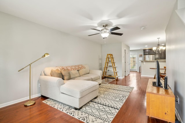 living room featuring dark wood-type flooring and ceiling fan with notable chandelier