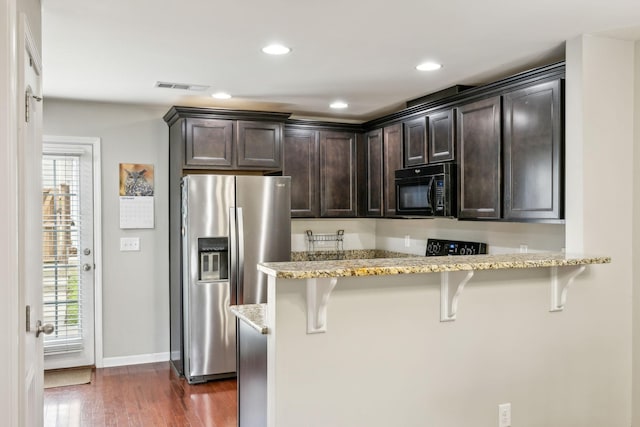 kitchen with light stone countertops, kitchen peninsula, a kitchen bar, and stainless steel fridge with ice dispenser