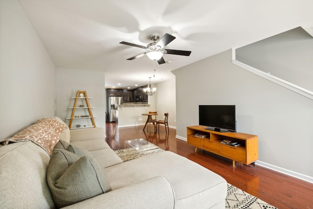 living room with dark wood-type flooring and ceiling fan with notable chandelier