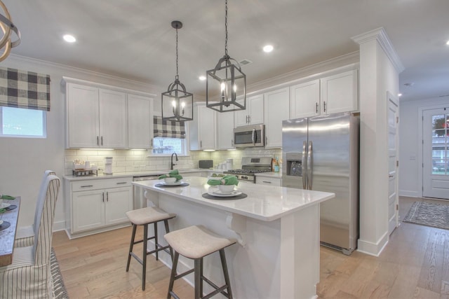 kitchen featuring stainless steel appliances, white cabinetry, hanging light fixtures, and a center island