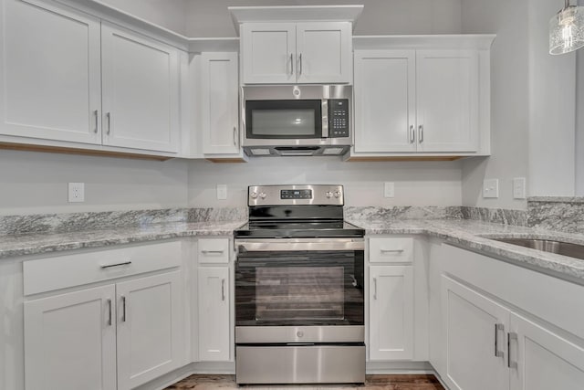 kitchen with light stone countertops, stainless steel appliances, hanging light fixtures, and white cabinets