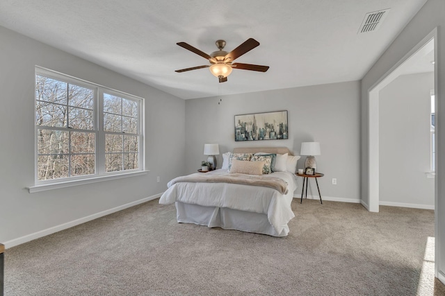 bedroom featuring light carpet, baseboards, visible vents, and a ceiling fan