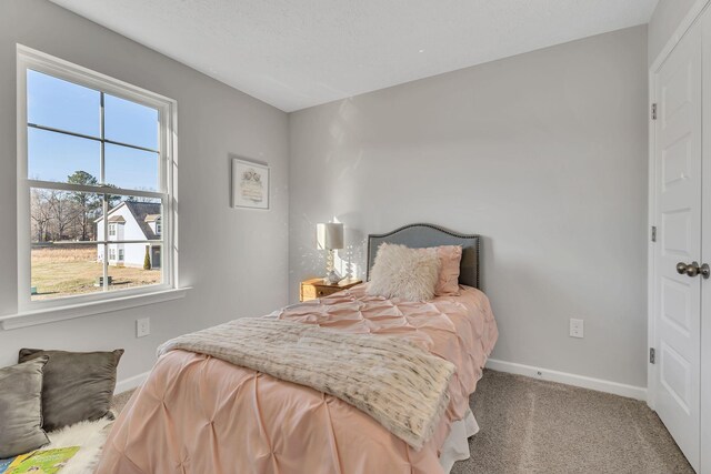 bedroom with a textured ceiling, carpet floors, and baseboards