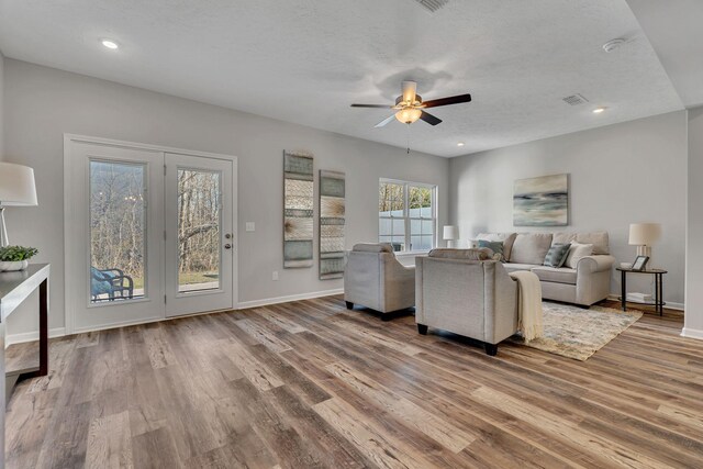 living area with a textured ceiling, recessed lighting, wood finished floors, a ceiling fan, and baseboards