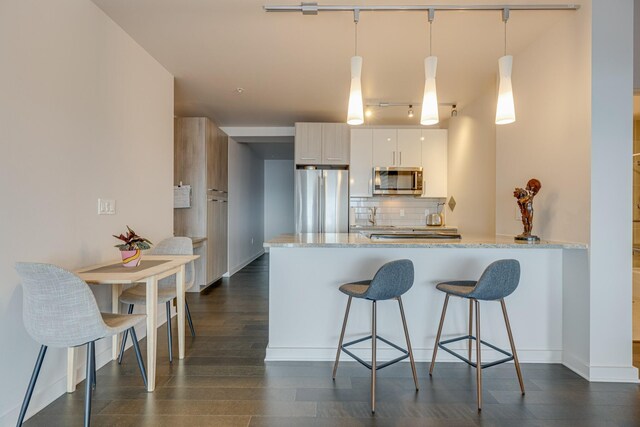515 Church St Unit 3208, Nashville, TN 37219 - kitchen featuring appliances with stainless steel finishes, decorative light fixtures, white cabinetry, decorative backsplash, and kitchen peninsula