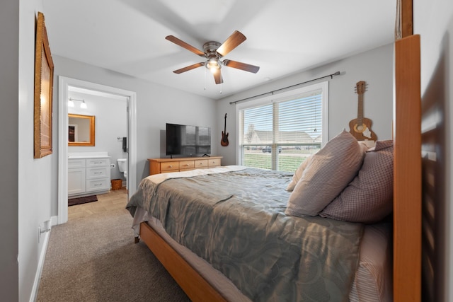 bedroom featuring ceiling fan, light colored carpet, and ensuite bath