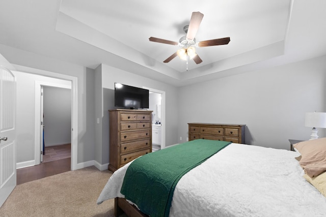 carpeted bedroom featuring connected bathroom, a raised ceiling, and ceiling fan