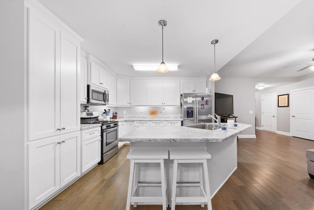 kitchen featuring white cabinetry, an island with sink, a kitchen bar, hanging light fixtures, and stainless steel appliances