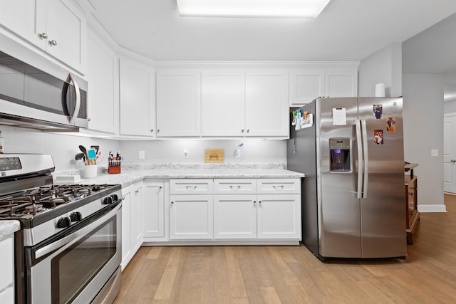 kitchen with appliances with stainless steel finishes, light wood-type flooring, white cabinets, and light stone counters