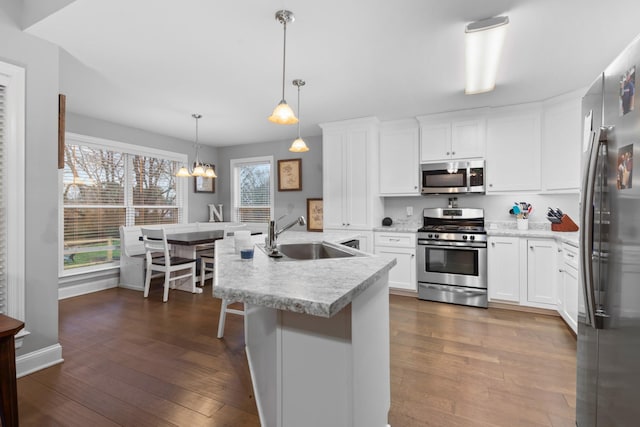 kitchen featuring sink, dark hardwood / wood-style flooring, pendant lighting, stainless steel appliances, and white cabinets