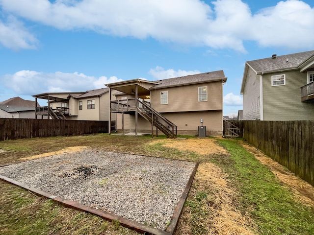 rear view of house with central AC unit and a lawn