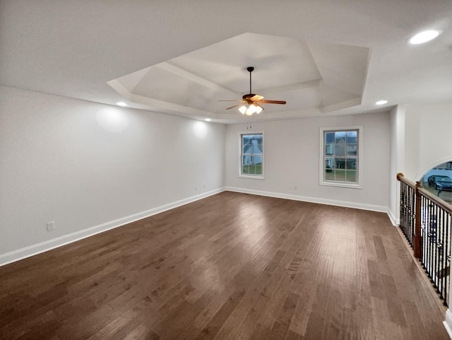 unfurnished living room featuring dark wood-type flooring, ceiling fan, and a tray ceiling