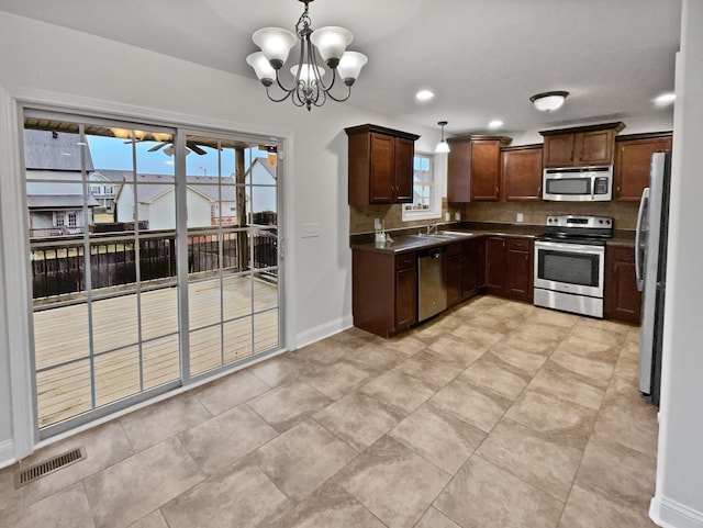 kitchen featuring sink, appliances with stainless steel finishes, hanging light fixtures, a notable chandelier, and decorative backsplash