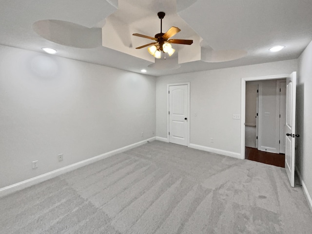 unfurnished bedroom with a raised ceiling, carpet, and ceiling fan