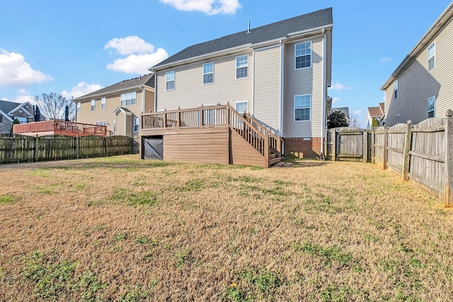 rear view of property with a wooden deck and a lawn