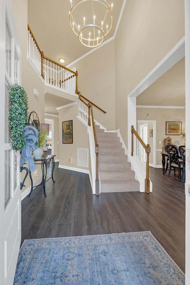 foyer featuring ornamental molding, dark hardwood / wood-style floors, a chandelier, and a high ceiling