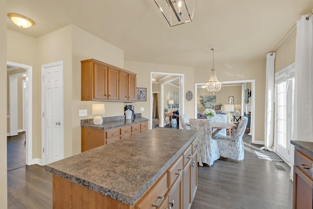 kitchen featuring dark hardwood / wood-style flooring, a kitchen island, pendant lighting, and a chandelier