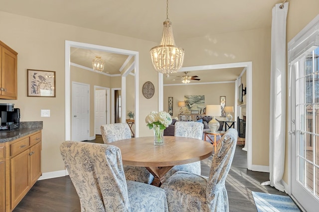 dining space with dark hardwood / wood-style flooring, crown molding, and ceiling fan with notable chandelier