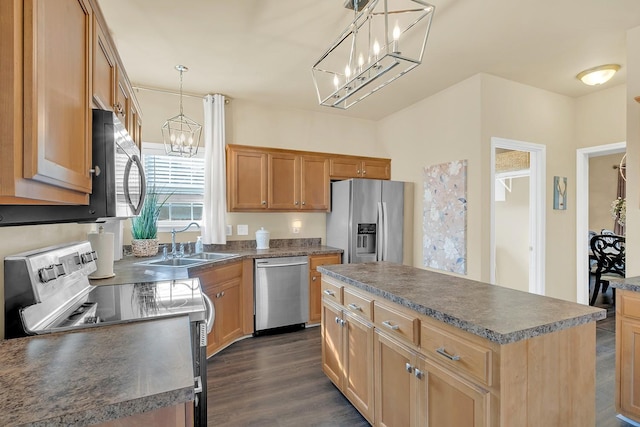 kitchen featuring stainless steel appliances, decorative light fixtures, a center island, and sink