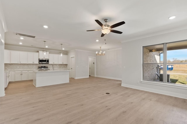 unfurnished living room with crown molding, ceiling fan with notable chandelier, and light hardwood / wood-style floors