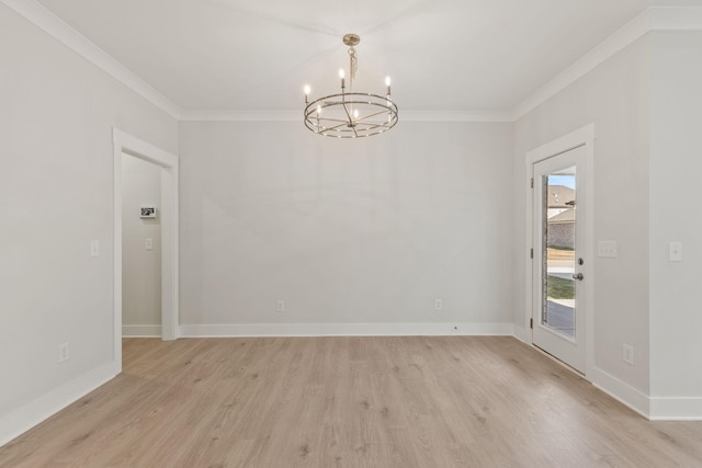 spare room with a notable chandelier, ornamental molding, and light hardwood / wood-style floors