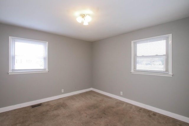 empty room featuring baseboards, visible vents, and carpet flooring