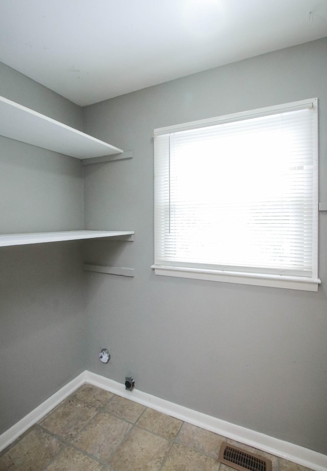 clothes washing area with laundry area, visible vents, baseboards, and a healthy amount of sunlight