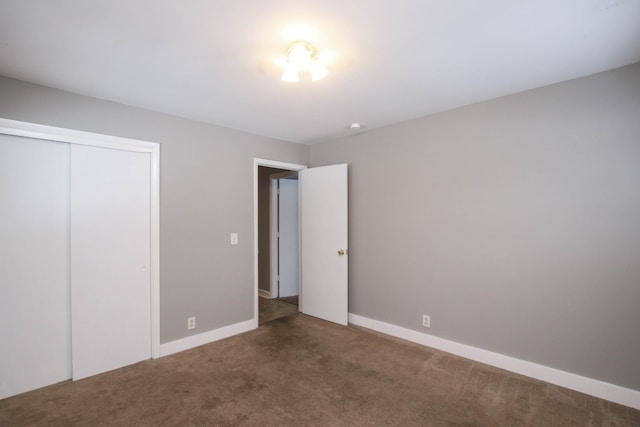 unfurnished bedroom with carpet floors, a closet, and baseboards