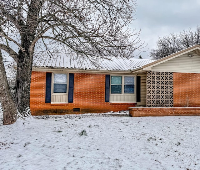 exterior space with metal roof, brick siding, and crawl space