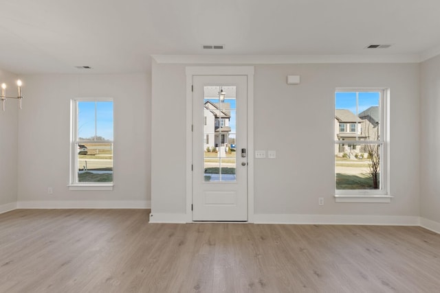 foyer featuring crown molding, a notable chandelier, and light wood-type flooring