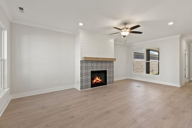 unfurnished living room with crown molding, light hardwood / wood-style flooring, a tile fireplace, and ceiling fan