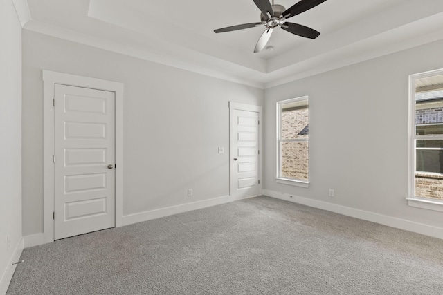 spare room featuring ceiling fan, ornamental molding, a tray ceiling, and carpet floors