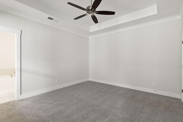 carpeted empty room with a raised ceiling, ornamental molding, and ceiling fan