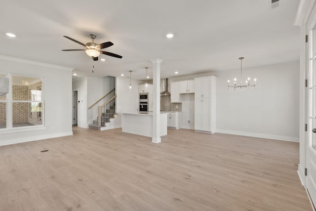 unfurnished living room featuring ceiling fan with notable chandelier and light hardwood / wood-style floors