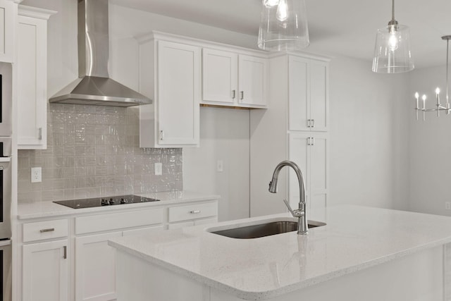 kitchen featuring a kitchen island with sink, white cabinets, black electric cooktop, decorative light fixtures, and wall chimney exhaust hood