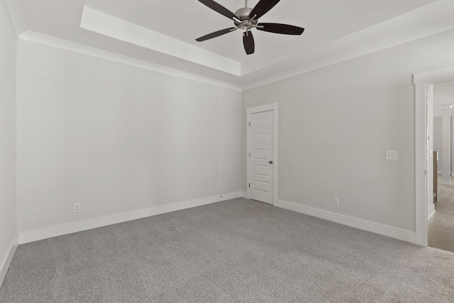 unfurnished room featuring crown molding, a tray ceiling, light colored carpet, and ceiling fan