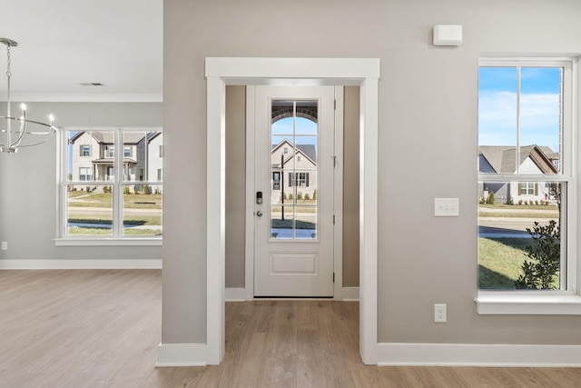 foyer with plenty of natural light, light hardwood / wood-style floors, and a chandelier