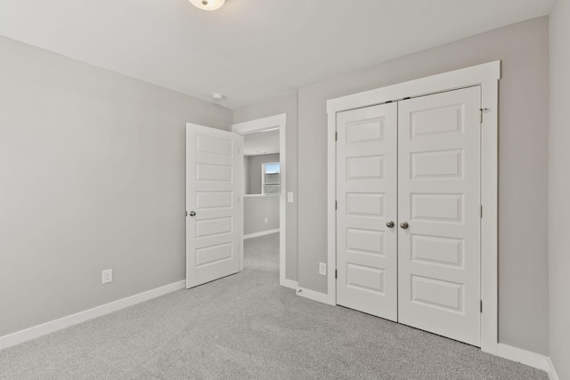 unfurnished bedroom featuring light carpet and a closet