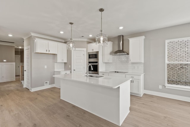 kitchen featuring appliances with stainless steel finishes, wall chimney exhaust hood, sink, and white cabinets