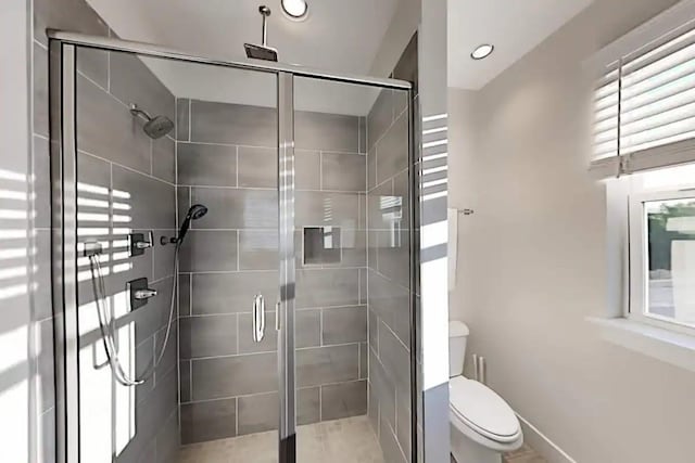 bathroom with a shower with door and toilet